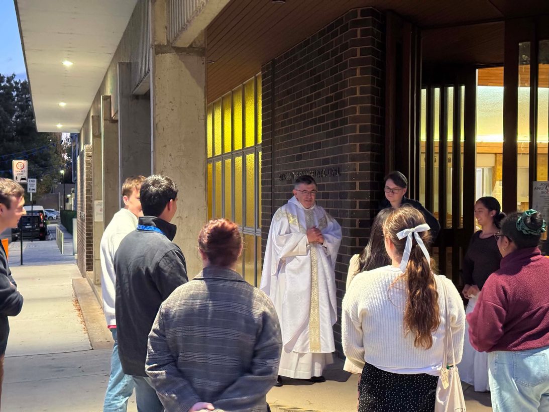 Fr Anthony Walsh OP speaking with students outside the chapel at dusk